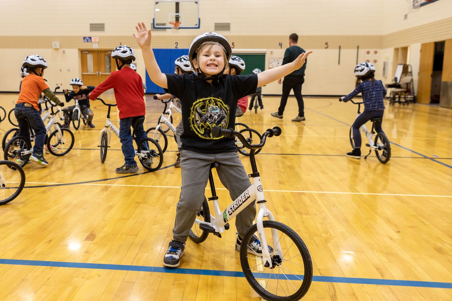 A triumphant child celebrates riding a bike in the All Kids Bike Kindergarten PE Program