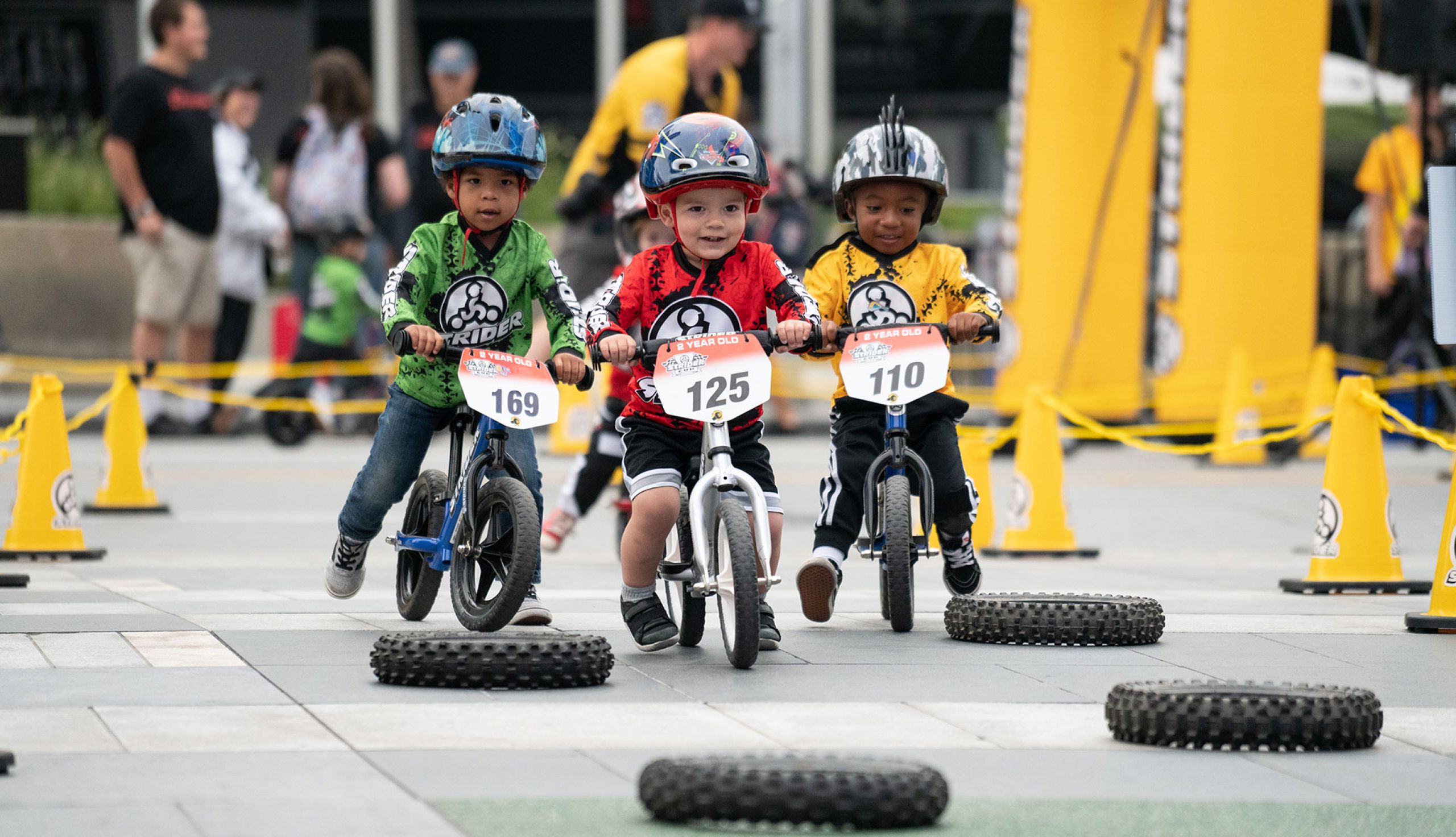 Toddlers racing  over tire obstacles in Strider Cup event