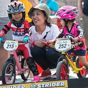 A mother smiles at her child at the starting line of a Strider Cup race.