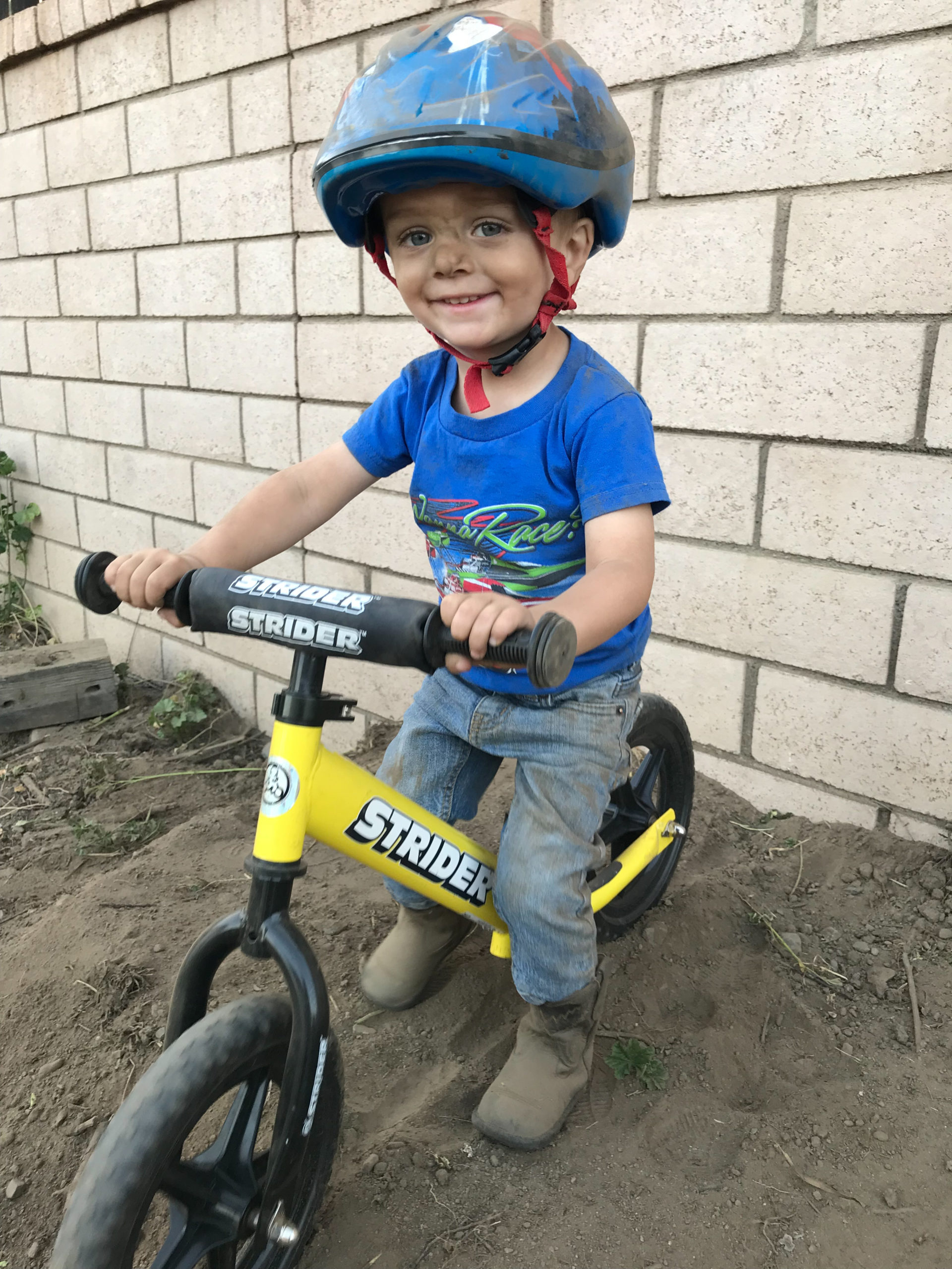 Young boy covered in dirt riding yellow 12 Sport