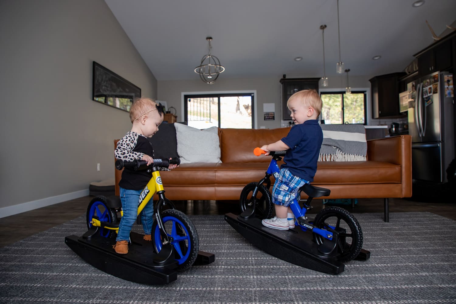 Two babies on yellow and blue Strider Sport Rocking Bikes