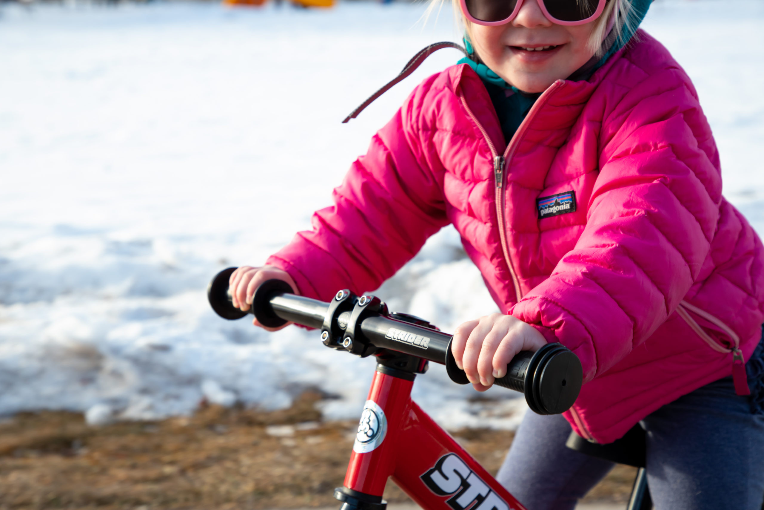 Close-up of Girl riding red 12 Sport with Strider Aluminum Flat Handlebar