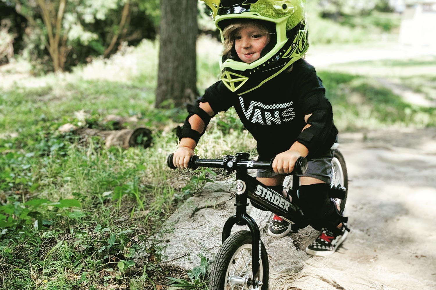 A child on a black Strider balance bike with an ST-R Stem Adapter and ST-R Carbon Handlebar